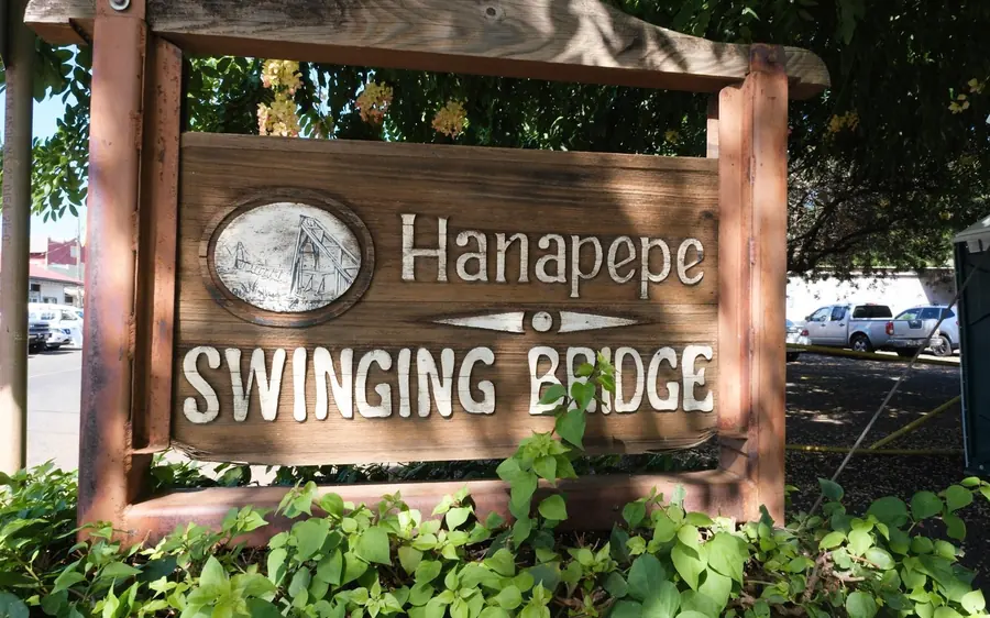 The Hanapepe Swinging Bridge sign under trees on Kauai
