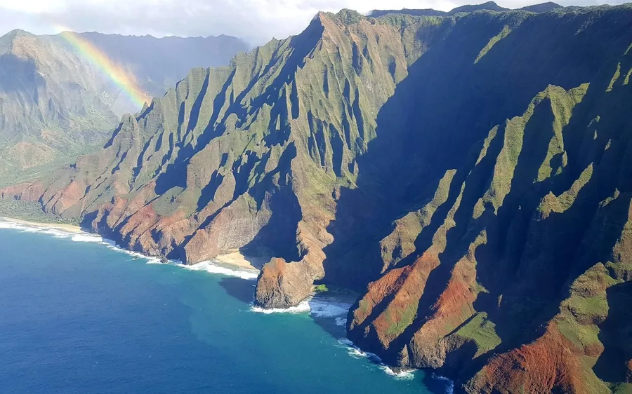 A small fixed-wing plane flying above the Na Pali Coast on Kauai