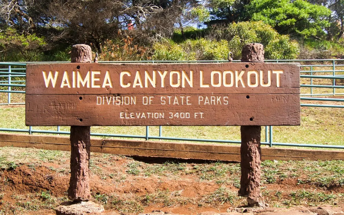 The wooden Waimea Canyon Lookout sign at the roadside on the canyon rim